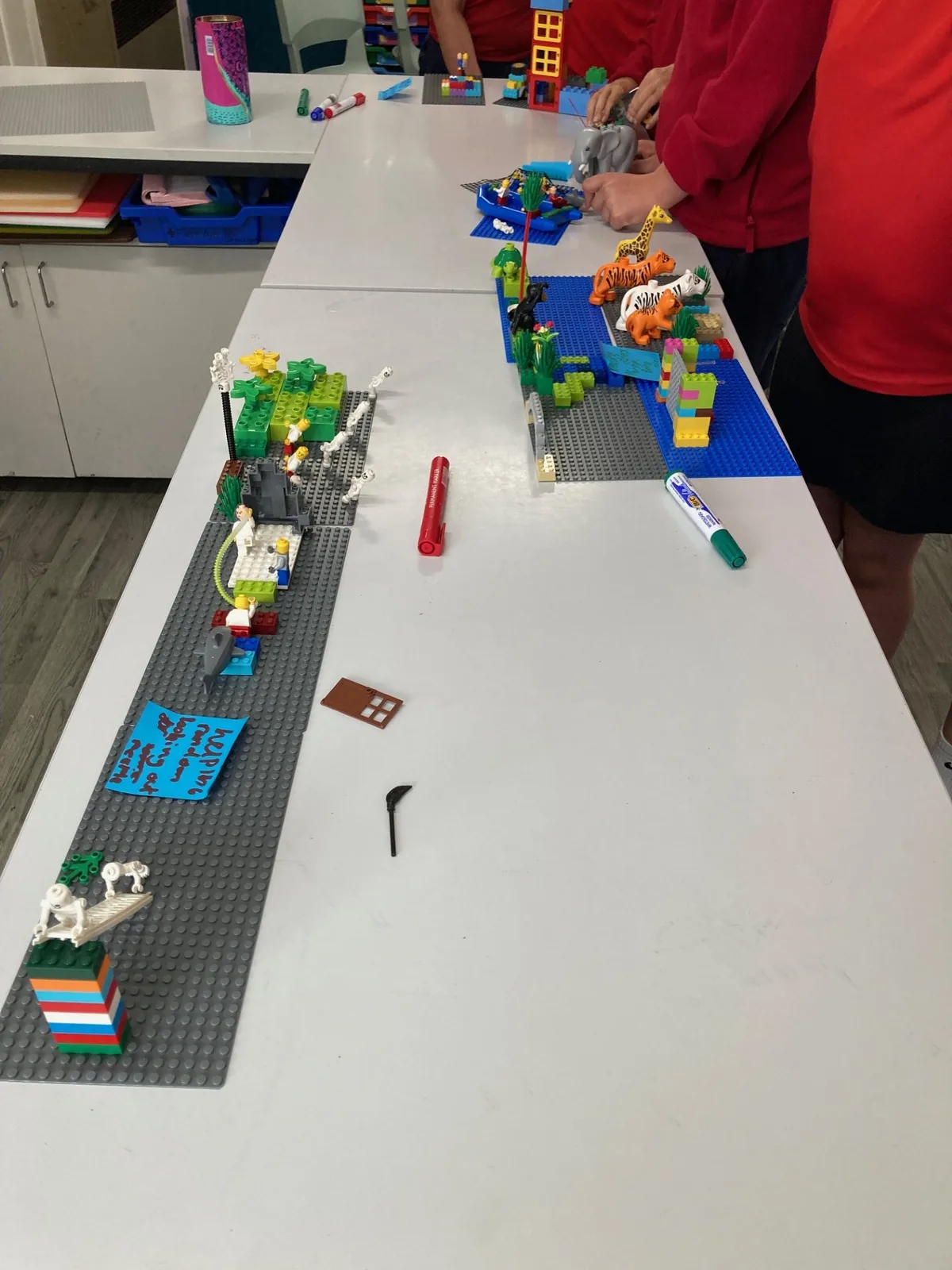 Year 5 pupils' hands combining LEGO® models into a shared playground landscape